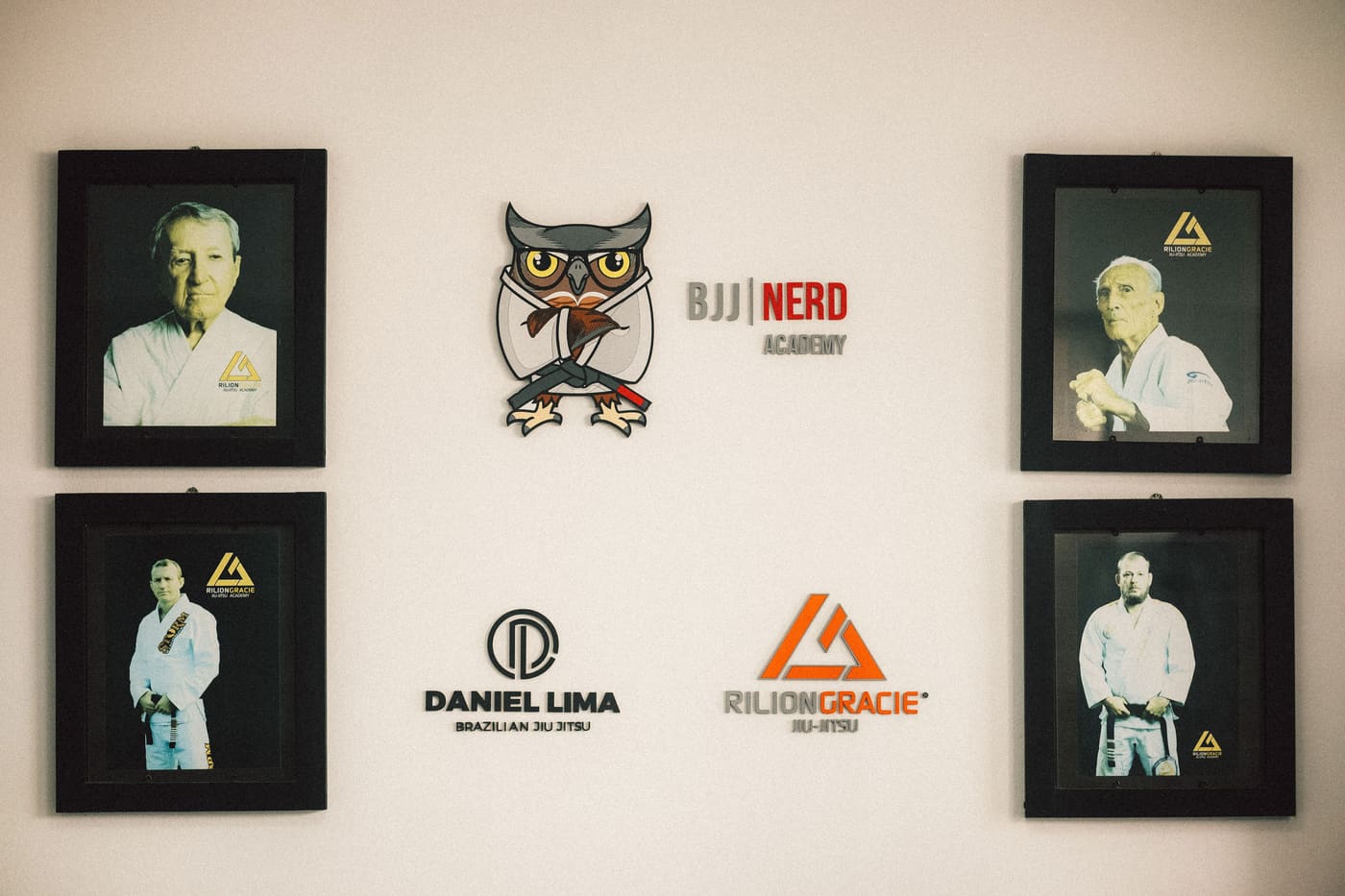 A parede da BJJ Nerd Academy com fotos da equipe e o logo da coruja